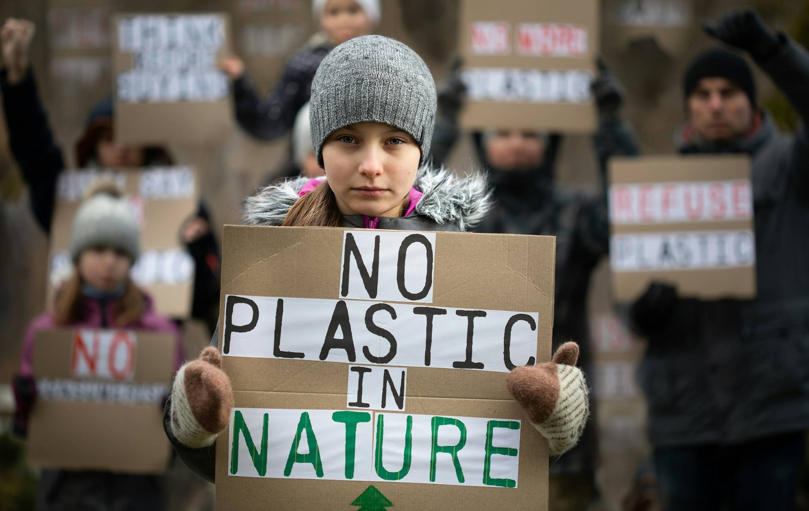 girl holding a sign that says no plastic in nature