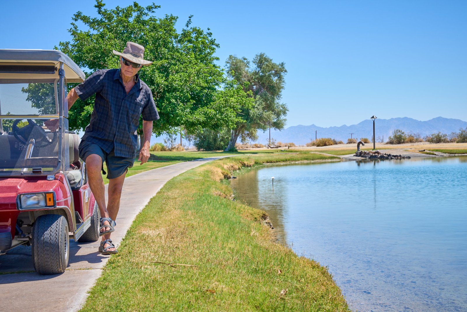 Mark Carrington exits his golf cart to look out on Lake Tamarisk, a man-made lake in Desert Center, Calif., on May 8, 2023. Credit: Alex Gould