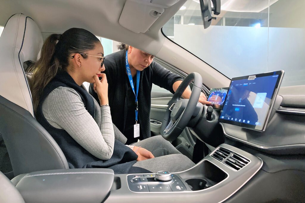 Paulina Hernández takes time to learn about her new BYD King plug-in hybrid sedan from sales rep Veronica Montoya at the BYD Santa Fe showroom in Mexico City. Credit: Natasha Pizzey