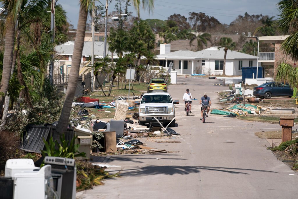 People ride bicycles through storm debris in the aftermath of Hurricane Milton on Thursday in Englewood, Fla. Credit: Sean Rayford/Getty Images