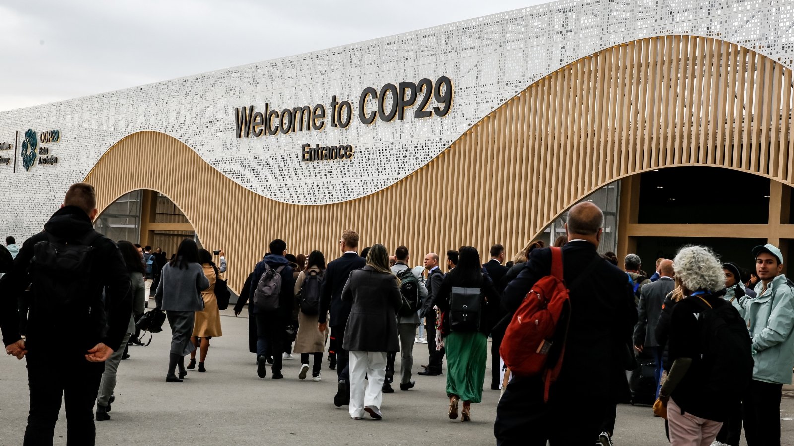 Participants walk by an entrance of COP29, UN Climate Change Conference venue, an event held by UNFCCC in Baku Olympic Stadium.